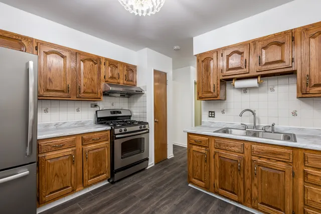 a kitchen with stainless steel appliances granite countertop a sink a stove a refrigerator cabinets and wooden floor