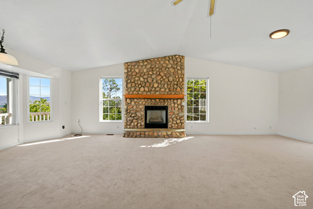 Vaulted ceiling, large windows, stone fireplace with wood mantel, and carpeting