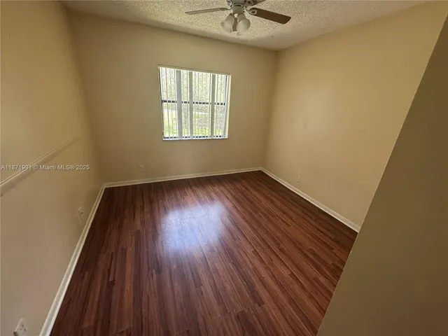 an empty room with a hardwood and windows