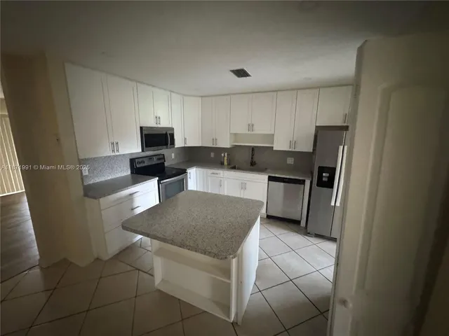 a kitchen with stainless steel appliances granite countertop a refrigerator sink and stove