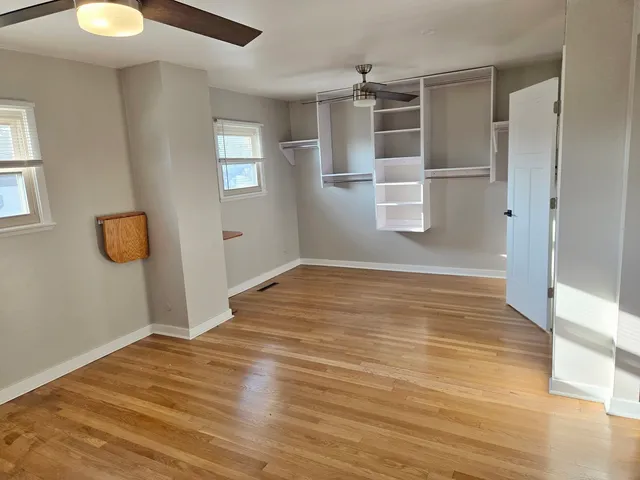 a view of empty room with wooden floor and fan