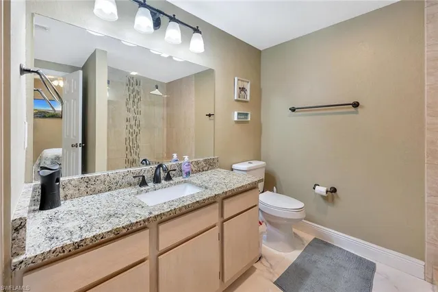 a bathroom with a granite countertop sink a toilet and a mirror