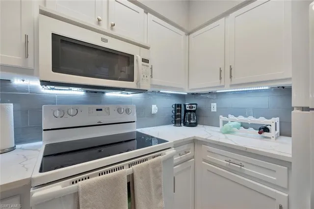 a kitchen with white cabinets and appliances
