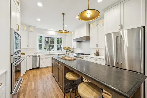 a kitchen with stainless steel appliances granite countertop a sink a stove and refrigerator