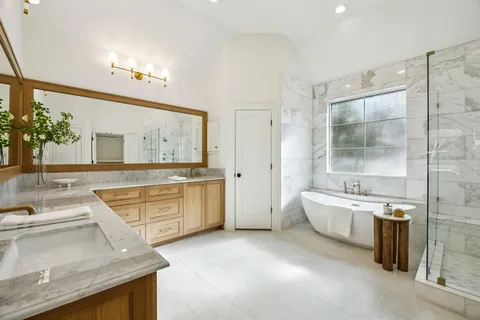 a large bathroom with a granite countertop double vanity sink a bathtub a mirror and a shower