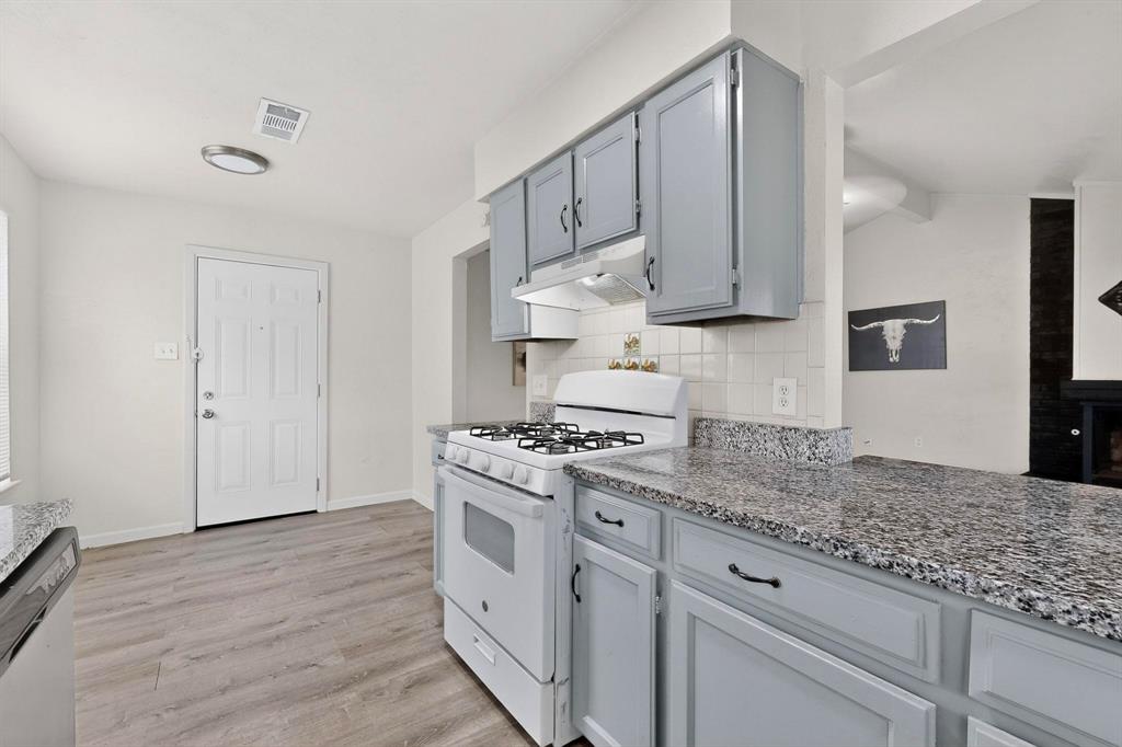 1538 Oakbrook Street Lancaster, TX 75134 - Photo 11 of 34 a kitchen with granite countertop cabinets stainless steel appliances and a wooden floor