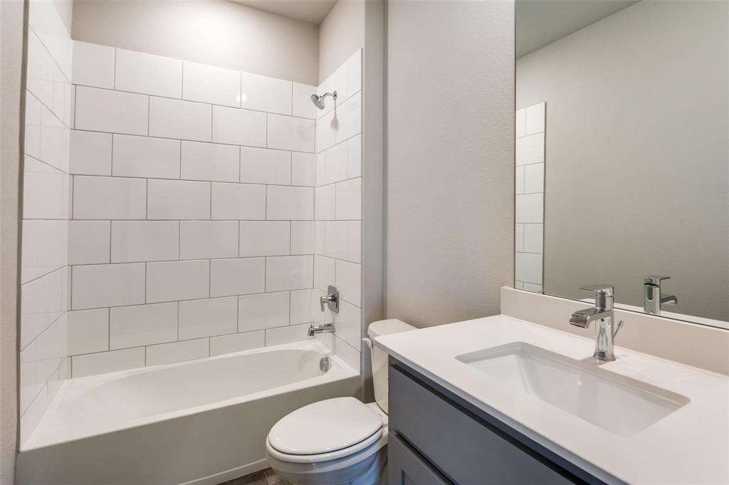 1517 Razorbill Road Denton, TX 76205 - Photo 23 of 25 Bathroom featuring a white subway tile tub surround, chrome fixtures, a single vanity with an integrated sink, and a large wall-mounted mirror