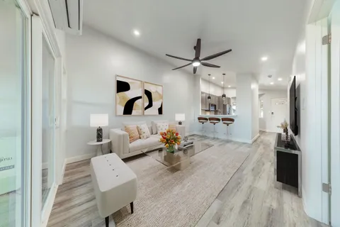 a living room with couches and kitchen view with wooden floor