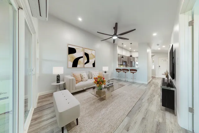 a living room with couches and kitchen view with wooden floor