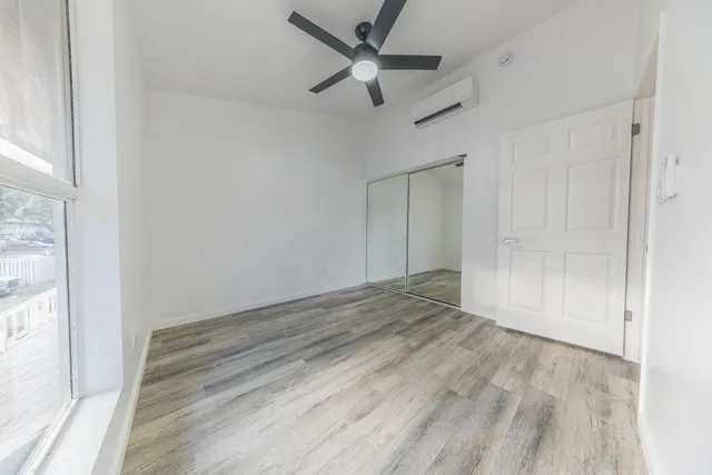a view of empty room with wooden floor and ceiling fan