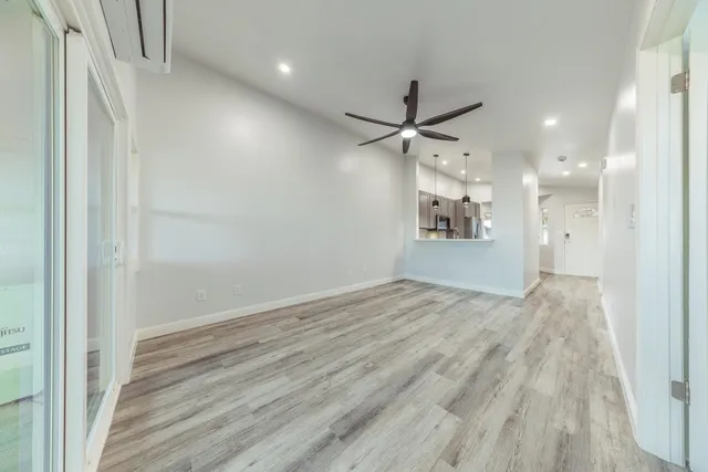 an empty room with wooden floor and a hallway