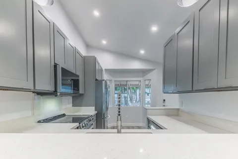 a kitchen with stainless steel appliances granite countertop a refrigerator a stove and a sink with wooden cabinets