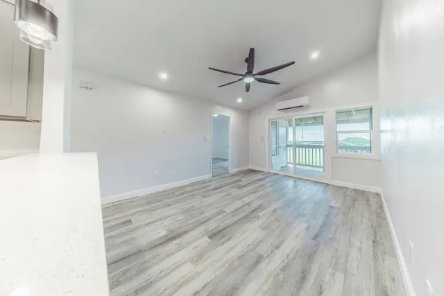 a view of an empty room with a window and wooden floor