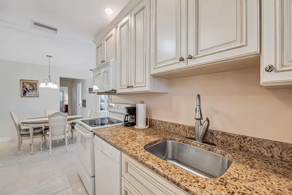 a kitchen with granite countertop a sink and white cabinets