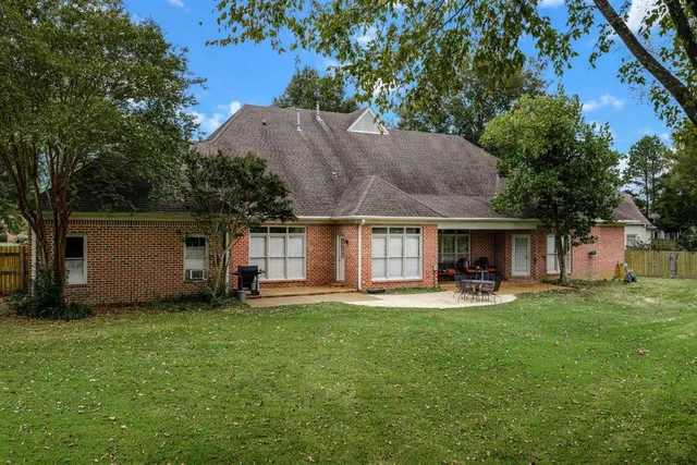 a backyard of a house with table and chairs and a large tree