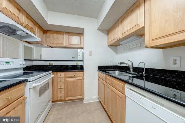 a kitchen with granite countertop white cabinets and white appliances