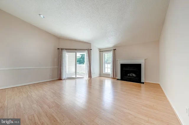 a view of empty room with wooden floor and fireplace