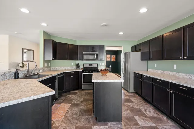 a kitchen with kitchen island granite countertop wooden cabinets and stainless steel appliances