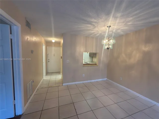 a view of an empty room and chandelier fan