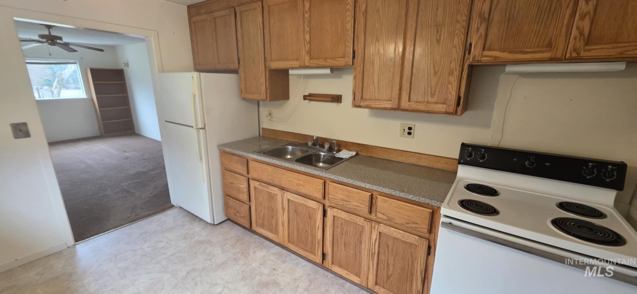 126 Rock Road Kamiah, ID 83536 - Photo 20 of 35 Kitchen featuring white appliances, brown cabinetry, a ceiling fan, and dark countertops