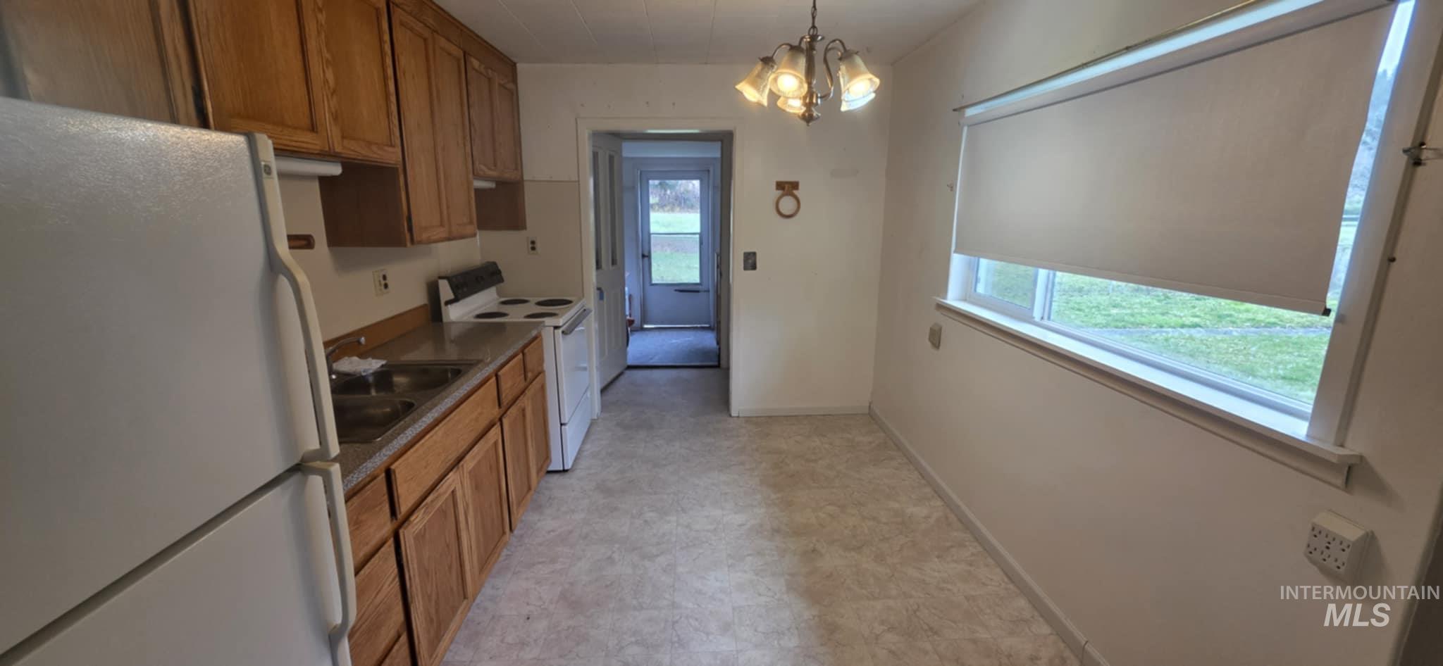 126 Rock Road Kamiah, ID 83536 - Photo 35 of 35 Kitchen featuring white appliances, brown cabinets, pendant lighting, a chandelier, and dark countertops