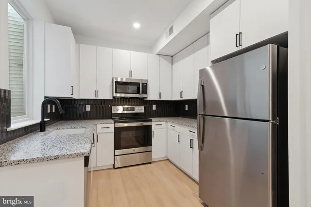 a kitchen with refrigerator a microwave a sink and cabinets