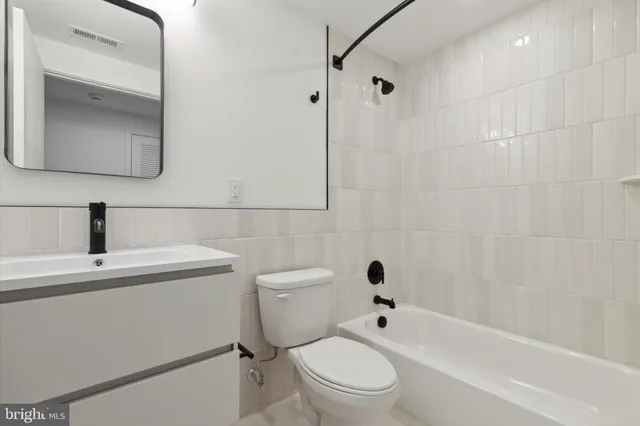 a bathroom with a toilet a sink a mirror and bathtub