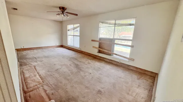 an empty room with windows and ceiling fan