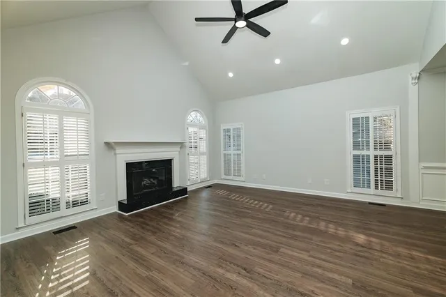 an empty room with wooden floor fireplace and windows