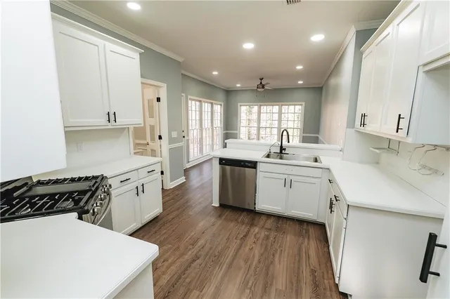 a kitchen with a sink a stove a refrigerator and white cabinets