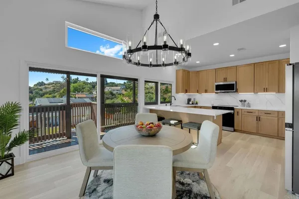 a kitchen with stainless steel appliances granite countertop a stove a refrigerator a sink dishwasher a dining table and chairs with wooden floor