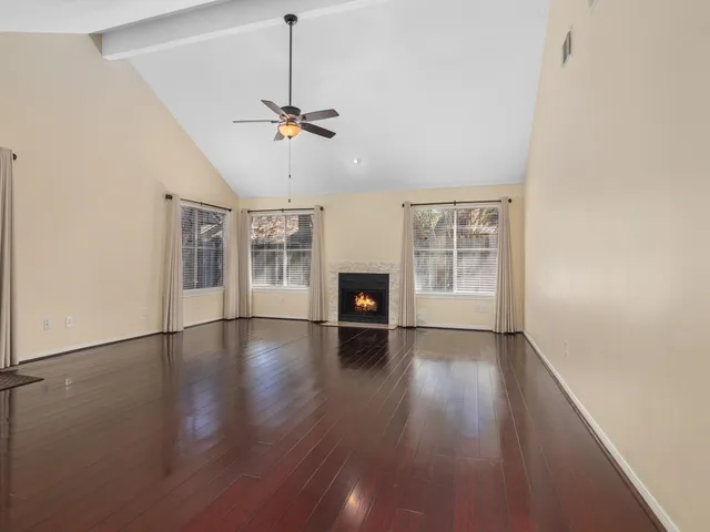 a view of a livingroom with wooden floor a ceiling fan and windows