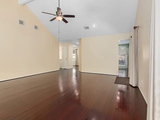 a view of a livingroom with wooden floor a ceiling fan and staircase