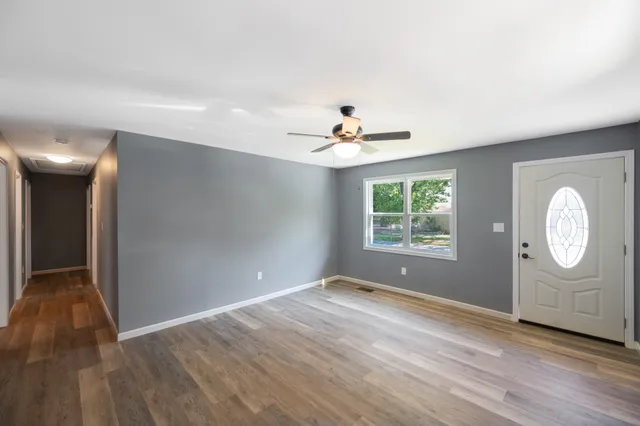 a view of an empty room with a window and wooden floor