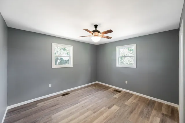 a view of a room with wooden floor and a ceiling fan