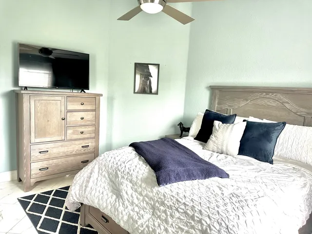 a bedroom with a large bed and a flat tv screen on dresser