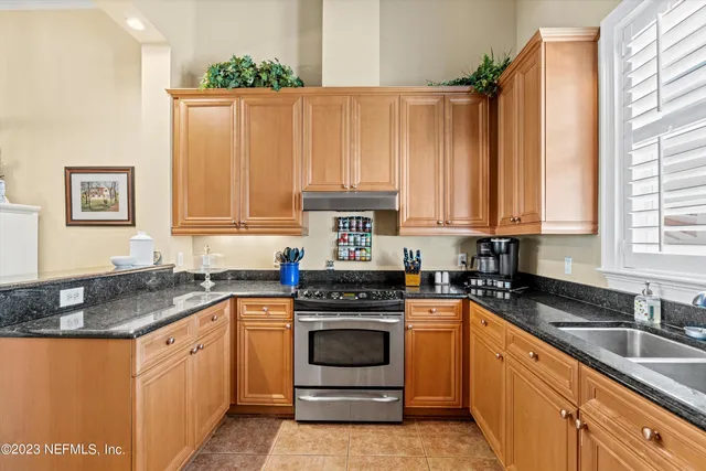 a kitchen with granite countertop a sink stove and cabinets