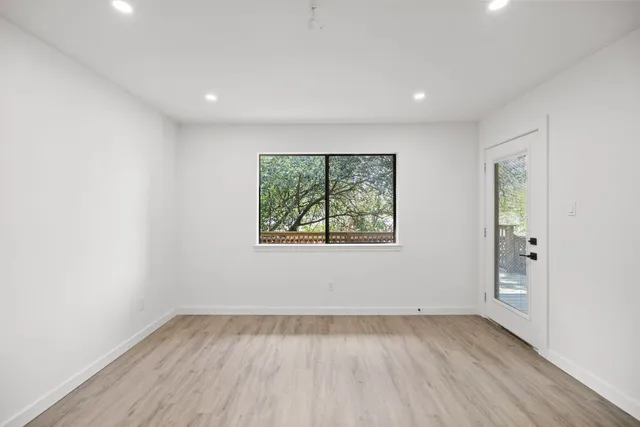 an empty room with wooden floor and windows