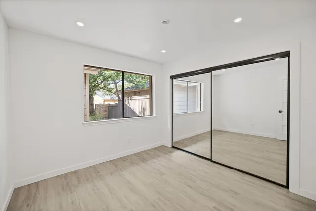 a view of an empty room with window and wooden floor