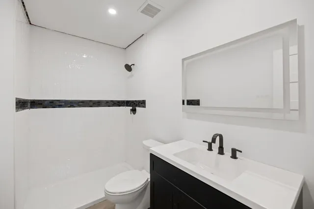 a bathroom with a granite countertop sink a toilet and a mirror