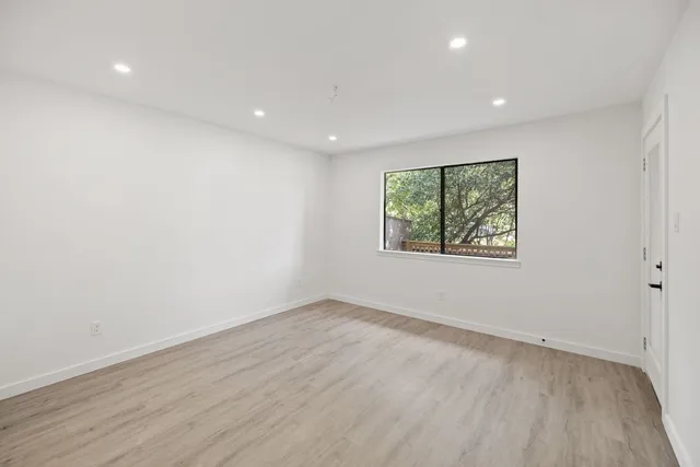 an empty room with wooden floor and window
