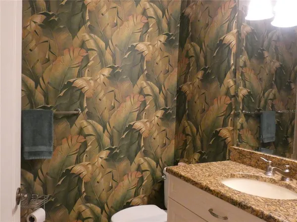 a bathroom with a granite countertop sink and a toilet