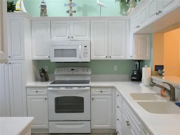a kitchen with granite countertop white cabinets and white appliances
