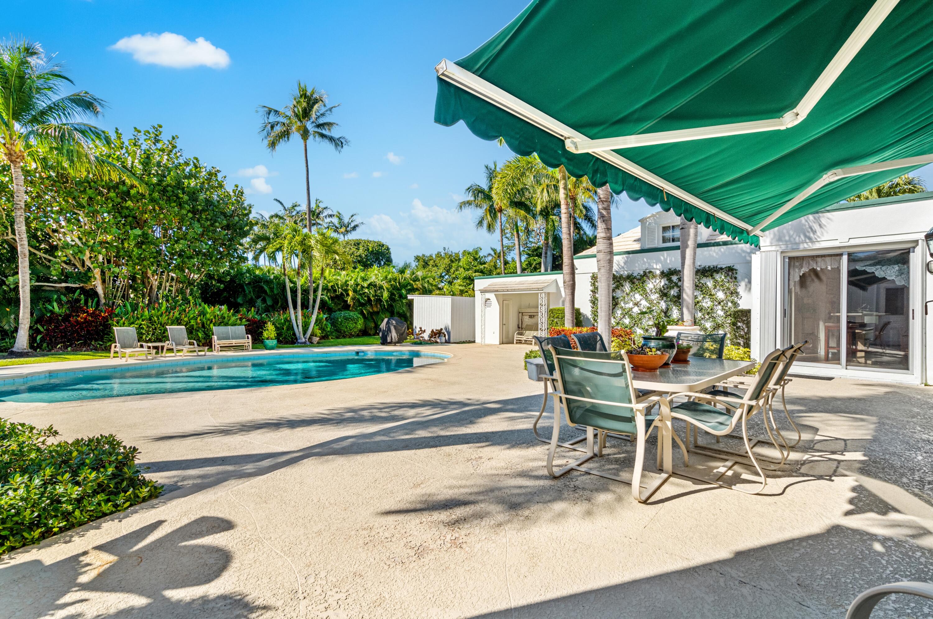 3224 North Ocean Boulevard Gulf Stream, FL 33483 - Photo 38 of 48 a white building with a table and chairs under an umbrella