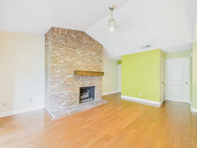 a view of empty room with a fireplace and wooden floor