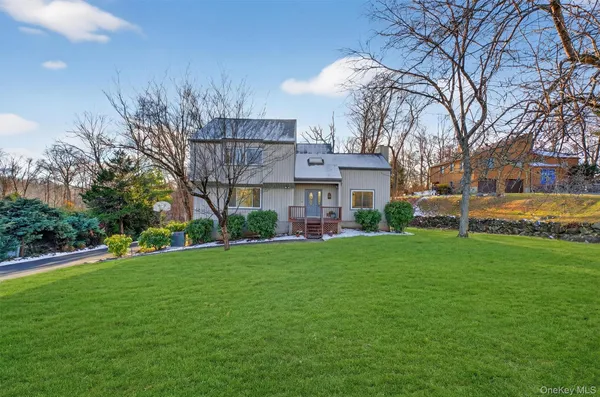 a view of a house next to a big yard and large trees