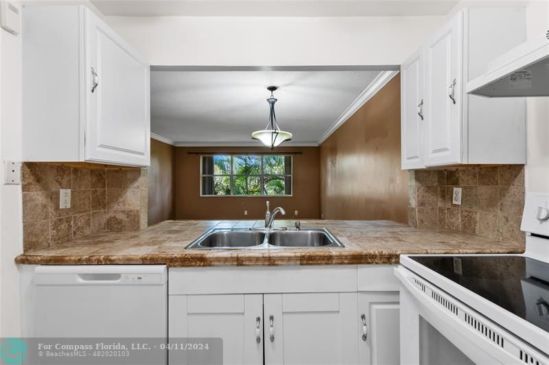 a kitchen with granite countertop a sink and white cabinets