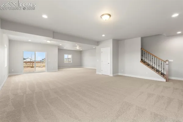 a view of an empty room and a kitchen with chandelier