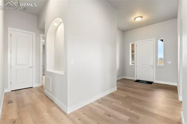 an empty room with wooden floor and windows