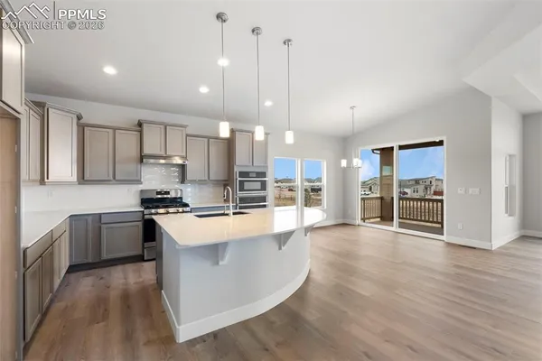 a large kitchen with stainless steel appliances lots of counter top space cabinets and a wooden floor